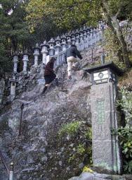 鎖を伝い急な斜面の岩山を登っている男性と女性の写真