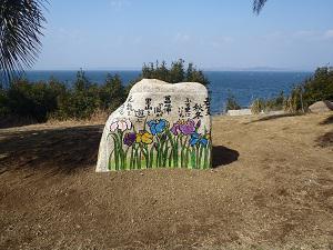 大きな石に紫色や水色、黄色の菖蒲の花と文章が書いてある石の作品の写真