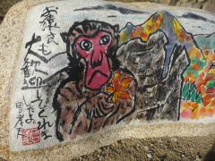 サルが紅葉の葉を手に持っている絵と文章が書いてある石の作品の写真