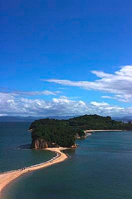 海に浮かぶ島から砂浜の道が続いている写真