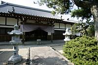 円満寺への道の左側に石灯籠、右側に植え込みがありの建物の入口にに大きな布が掛けられている写真