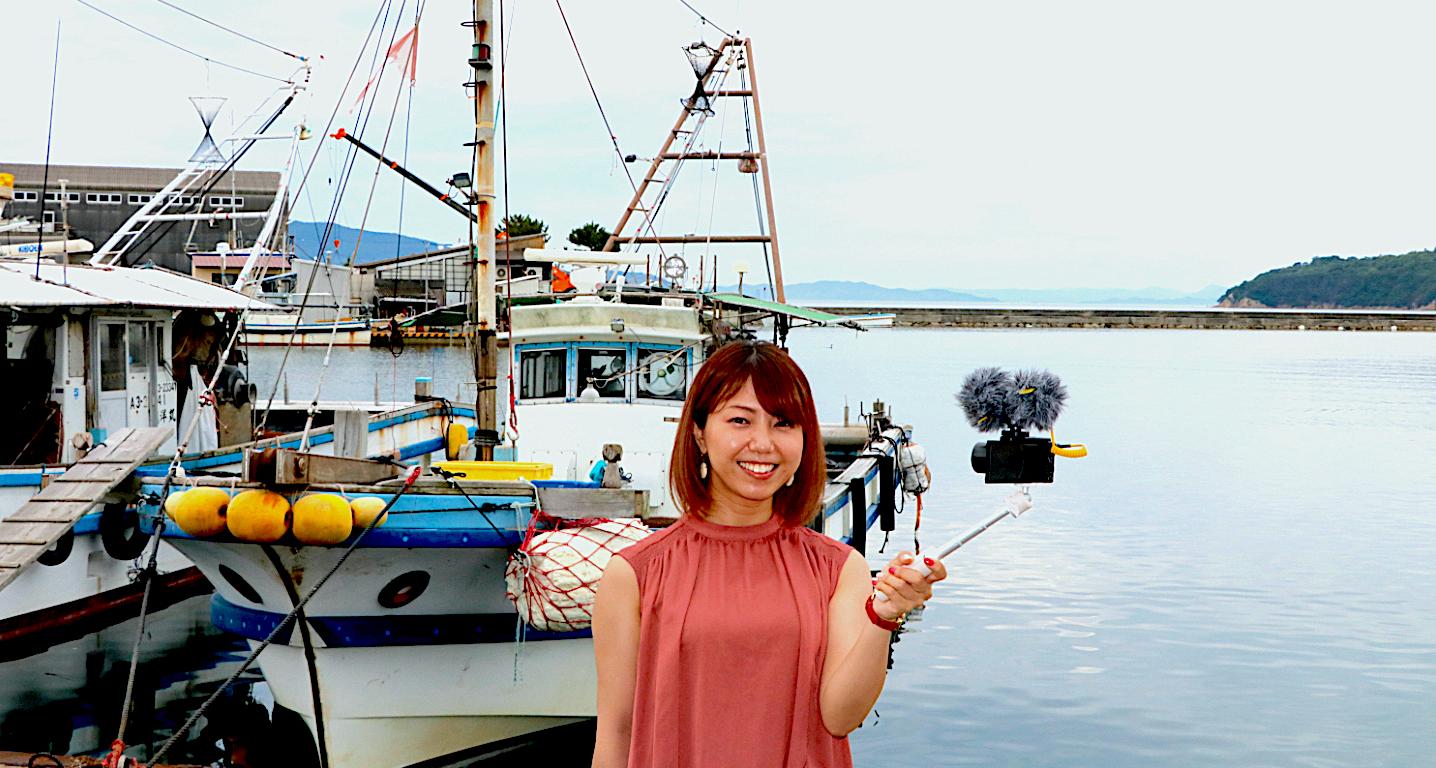 漁船の前で笑顔の吉田さん